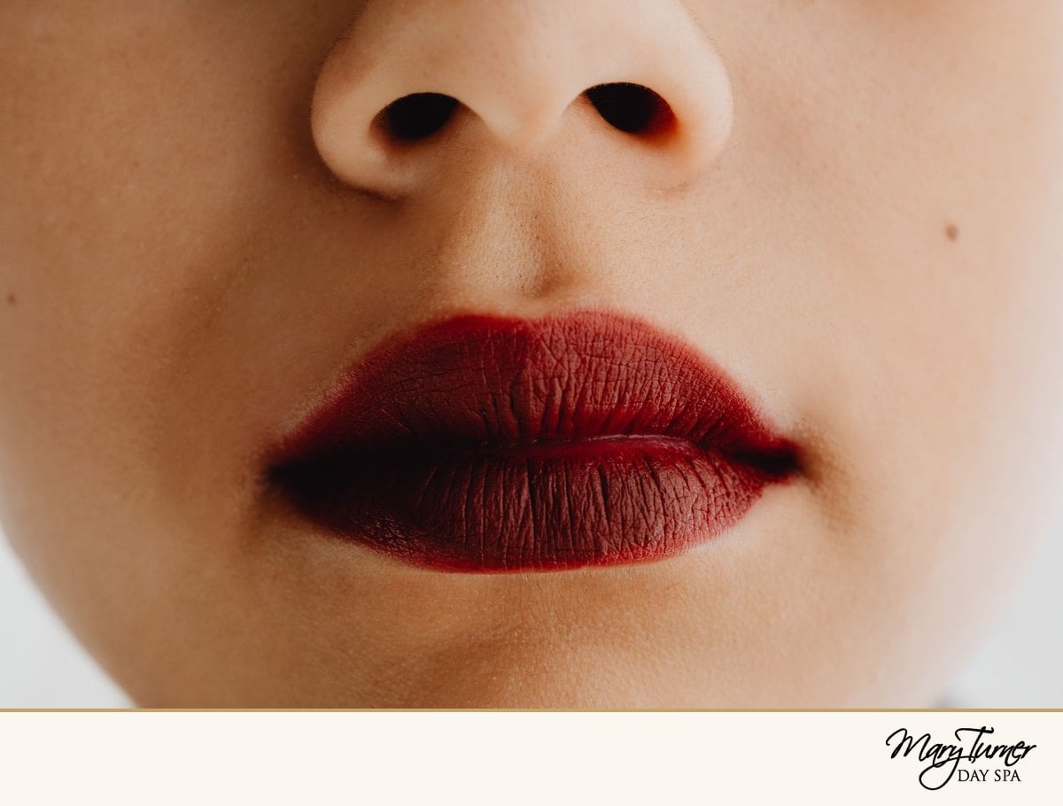 Close-up of lips wearing a deep cranberry-red lipstick