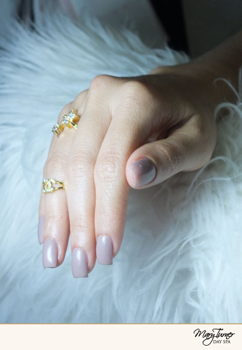 Close-up of a hand with milky, sheer nude nails on soft white fur